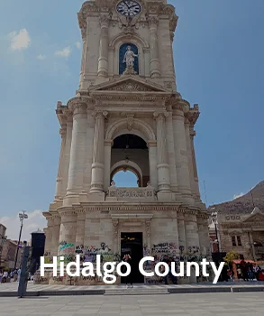 The grand clock tower in Hidalgo County with its ornate stonework, symbolizing the county’s historical and cultural significance.
