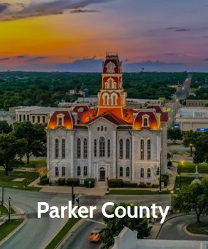 Parker County courthouse with its distinctive clock tower and illuminated architecture at sunset, representing Parker County’s historical and governmental significance.