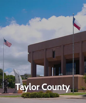 Taylor County courthouse with modern architecture, featuring the American and Texas flags in front, representing Taylor County's governmental services.