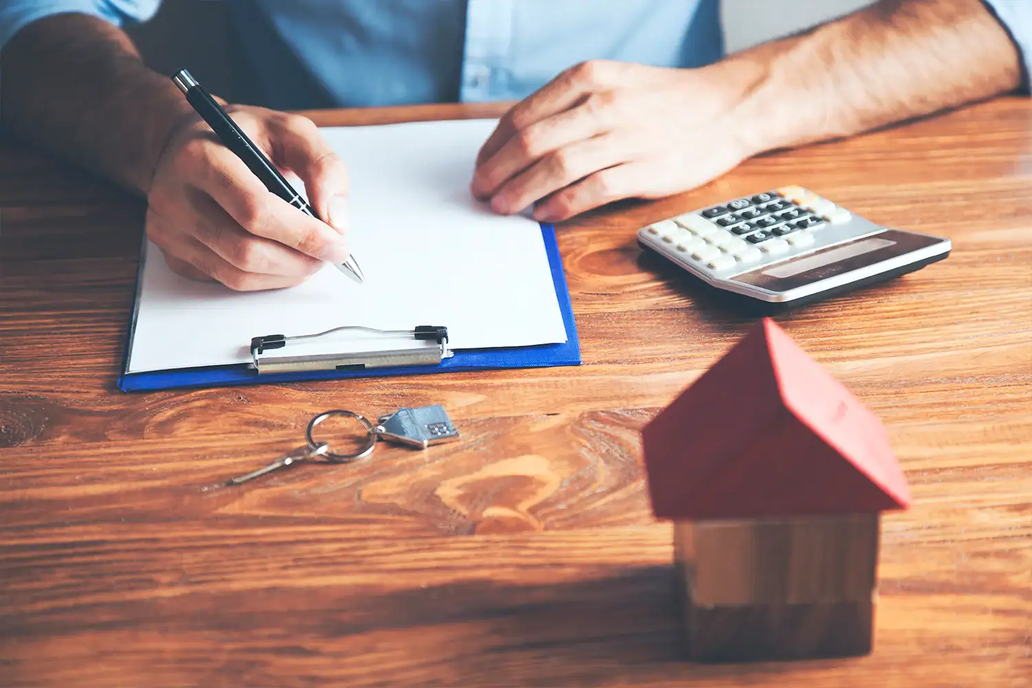 Homeowner reviewing property tax paperwork with calculator and house model, representing Houston property tax protest services by Tax Cutter.