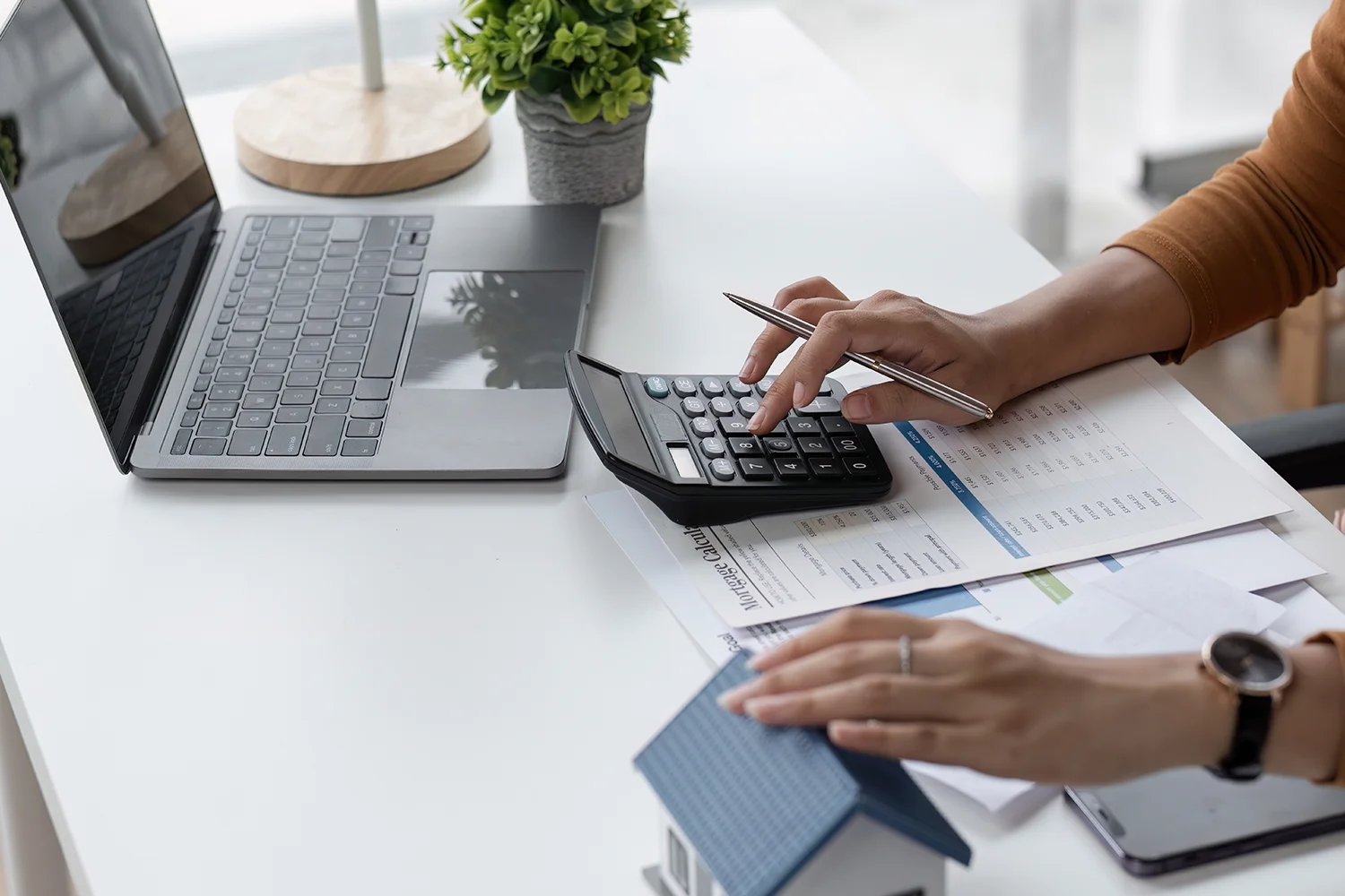 Homeowner calculating property taxes with calculator and laptop, representing Houston property tax protest and savings services by Tax Cutter.