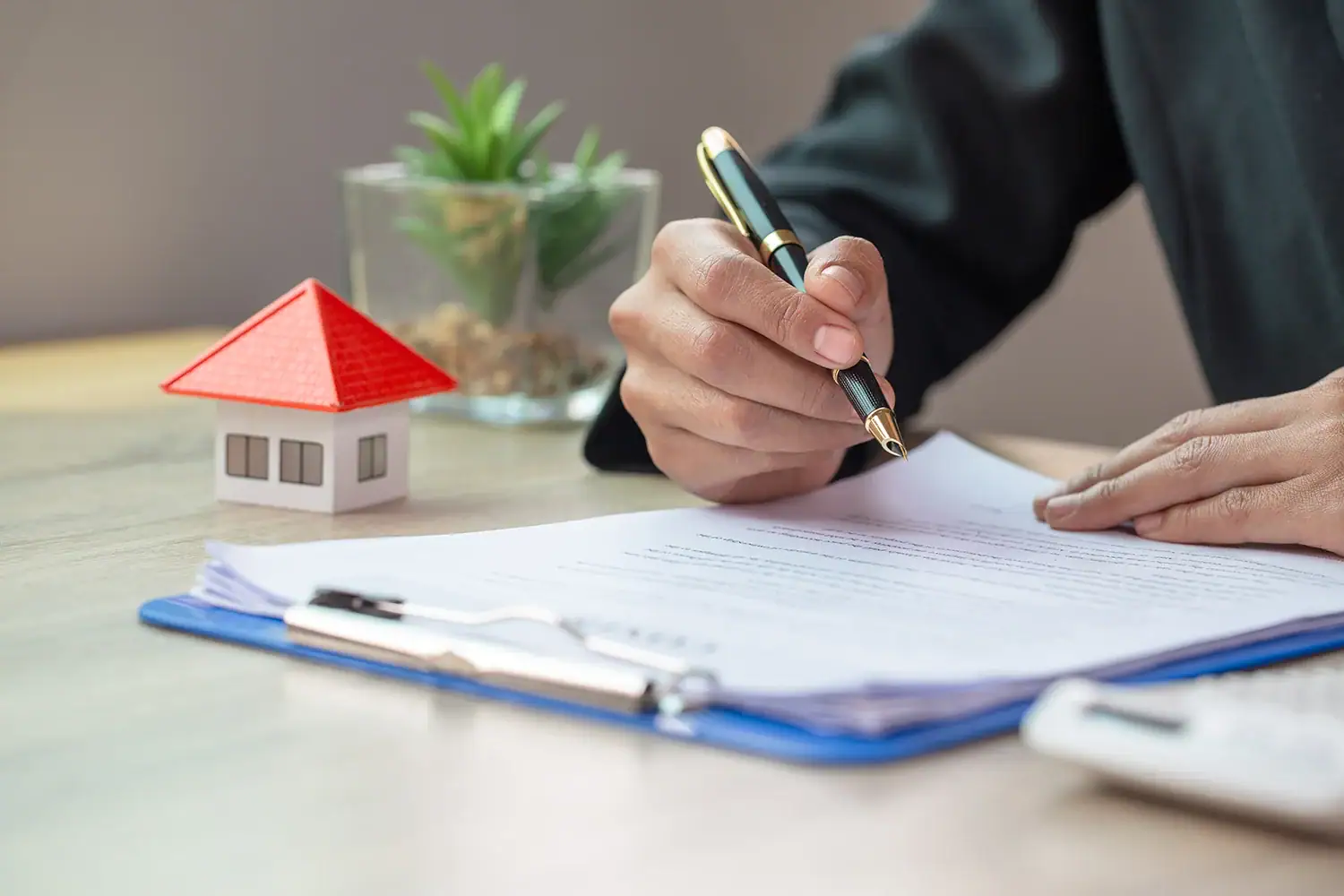 Homeowner signing property tax documents beside a house model, representing property tax protest and appeal services by Tax Cutter in Texas.