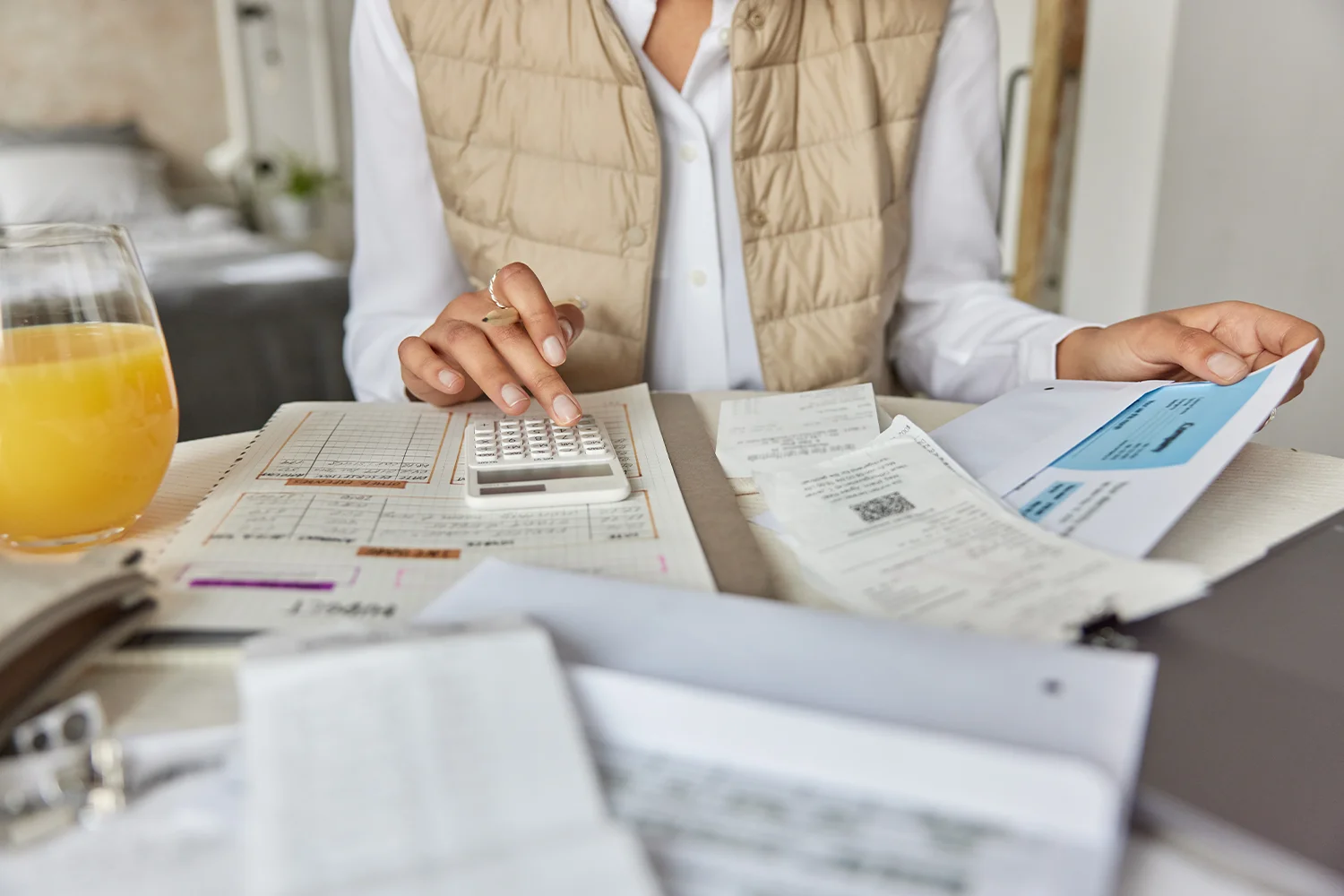 Homeowner reviewing bills and calculating property taxes with a calculator, representing Texas property tax protest and savings services by Tax Cutter.