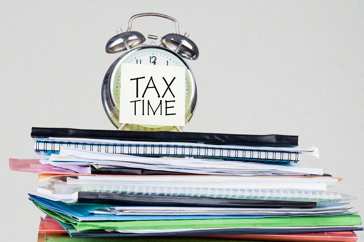 Stack of tax documents with clock showing tax time, representing property tax protest and appeal services by Tax Cutter.