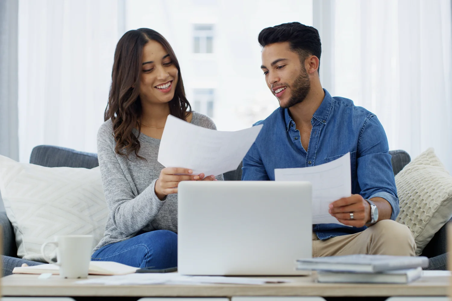 A Happy Couple reviewing property tax documents with a laptop at home, representing Houston property tax protest and savings services by Tax Cutter.