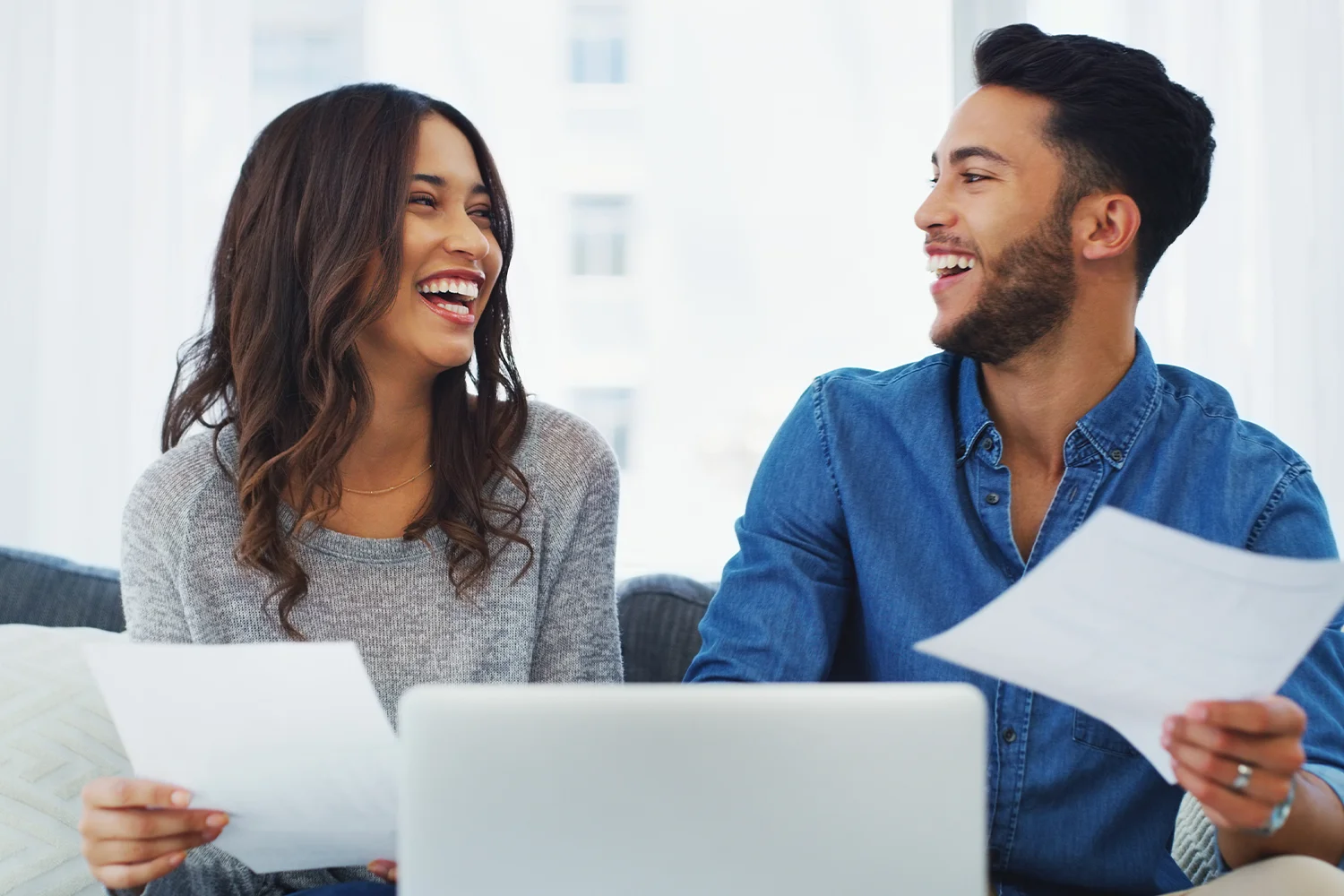 Happy homeowners reviewing property tax documents together at home, showing savings from Houston property tax protest services by Tax Cutter.